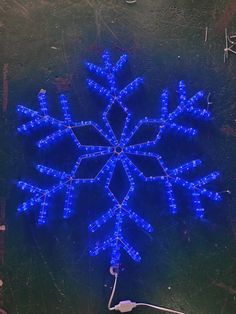 a snowflake made out of blue lights on a black surface with wires attached to it