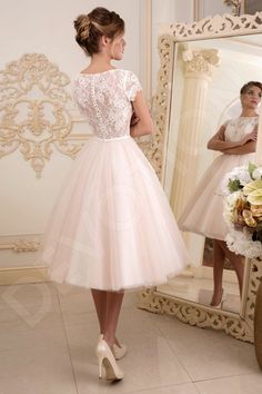 a woman standing in front of a mirror wearing a dress