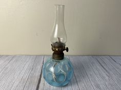 an old fashioned oil lamp sitting on top of a wooden table