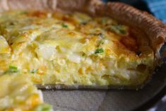 a close up of a quiche on a pan with one slice missing from it