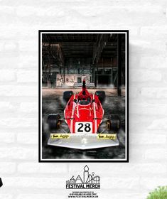 a red race car sitting in front of a white brick wall with the number 28 on it