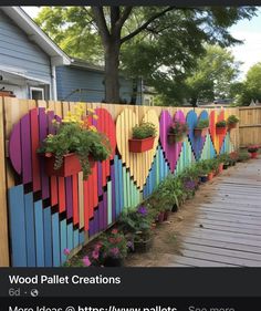 a wooden fence with colorful hearts painted on it and potted plants in the middle