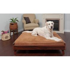 a large white dog laying on top of a bed in front of a fire place