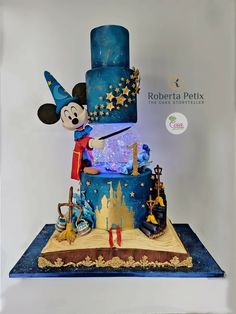 a mickey mouse birthday cake with blue frosting and gold stars on the top tier