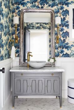 the bathroom is decorated with blue and white wallpaper, gold fixtures and a large mirror