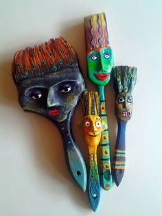 three different colored brushes with faces painted on them and one has an orange hairbrush