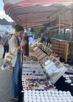 a woman standing in front of a table filled with lots of different types of items