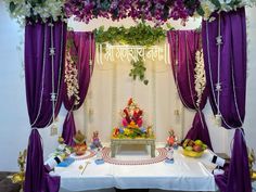 a decorated stage with purple drapes and flowers on the ceiling, surrounded by other decorations