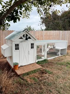 a chicken coop in the backyard next to a fence