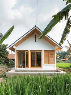 a small white house with wooden shutters and windows