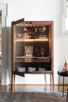 a wooden cabinet with glass doors and shelves filled with bottles, glasses and other items