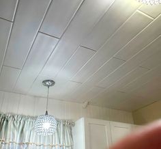 a light that is hanging from the ceiling in a room with white walls and curtains