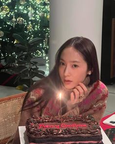 a woman sitting at a table in front of a cake with a candle on it