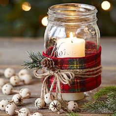 a mason jar filled with christmas decorations and a lit candle