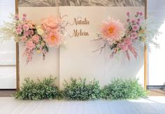 flowers are arranged on the side of a white wall with words written in gold foil