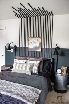 a bedroom with black and white striped walls, gray bedding, and an art work on the wall