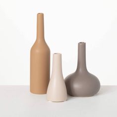 three different colored vases sitting next to each other on a white counter top,