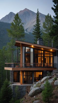 a modern house on the side of a mountain with trees and mountains in the background