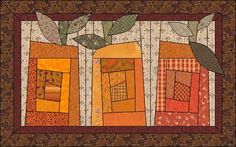 an orange and brown quilt with leaves on the top, in front of a wooden wall