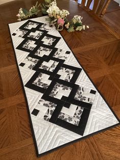 a black and white quilted table runner with flowers on the floor next to it