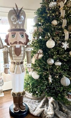 a large nutcracker standing next to a christmas tree