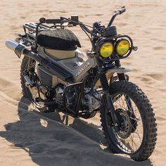 a motorcycle is parked in the sand at the beach with yellow lights on it's headlight