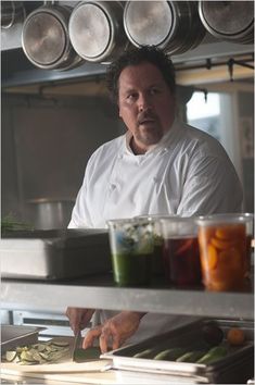 a man standing in front of a counter filled with vegetables and sauces on it