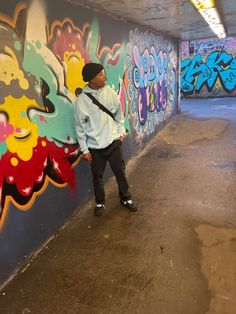 a man standing next to a wall covered in graffiti