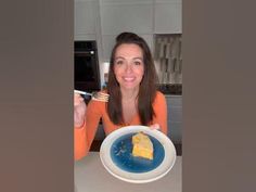 a woman sitting at a table with a plate and fork in front of her eating cake