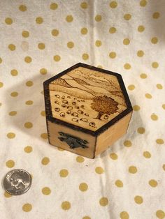 a wooden box sitting on top of a polka dot table cloth next to a coin