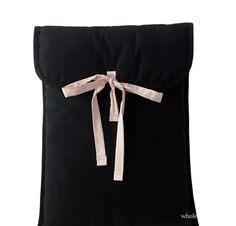 a black pillow with a pink ribbon tied around the front and back of it, on a white background