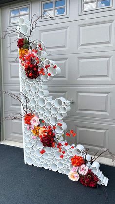 a white sculpture with flowers on it in front of a garage door