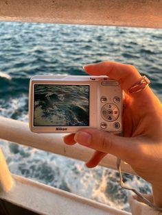 a person holding up a camera to take a photo on a boat with the ocean in the background