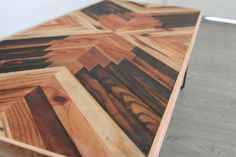 a wooden table with many different types of wood on the top and bottom, along with white walls