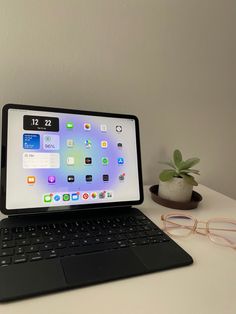 an open laptop computer sitting on top of a desk next to a potted plant