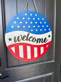 a welcome sign hanging on the front door of a house with stars and stripes painted on it