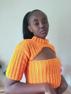 a woman in an orange sweater posing for the camera with her hands on her hips