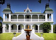 a large white house with a fountain in the front yard