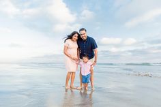 a man, woman and child are standing on the beach