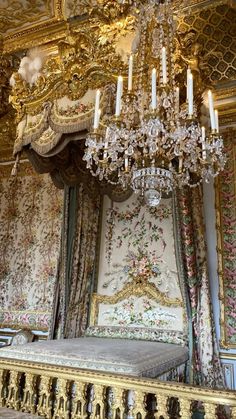 an ornate bed with chandelier and curtains in a palace like setting that is adorned with floral wallpaper