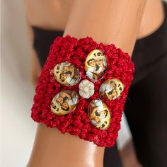 a close up of a person's arm wearing a red crochet bracelet