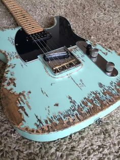 an old blue guitar sitting on the floor