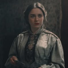 a woman in an old fashioned dress is holding something