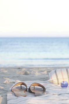 a pair of flip flops sitting on top of a sandy beach next to the ocean