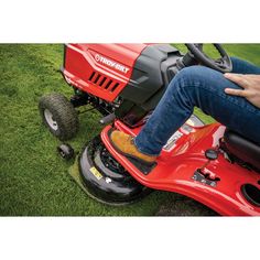 a man riding on the back of a red lawn mower