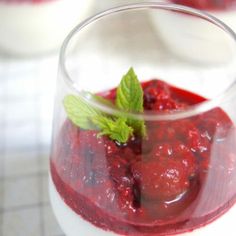 a close up of a dessert in a glass on a table with strawberries and mint