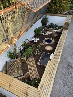 an elevated garden area with plants, rocks and gravel on the ground in front of a fence