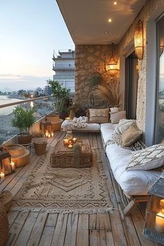 an outdoor living area with candles on the floor and pillows on the couches outside