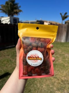 a person holding up a bag of food in their hand with palm trees in the background