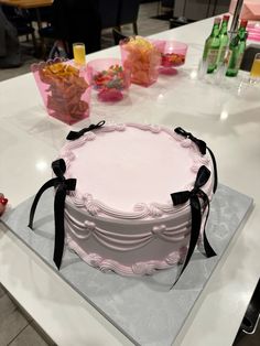 a pink cake sitting on top of a white counter next to bottles and utensils